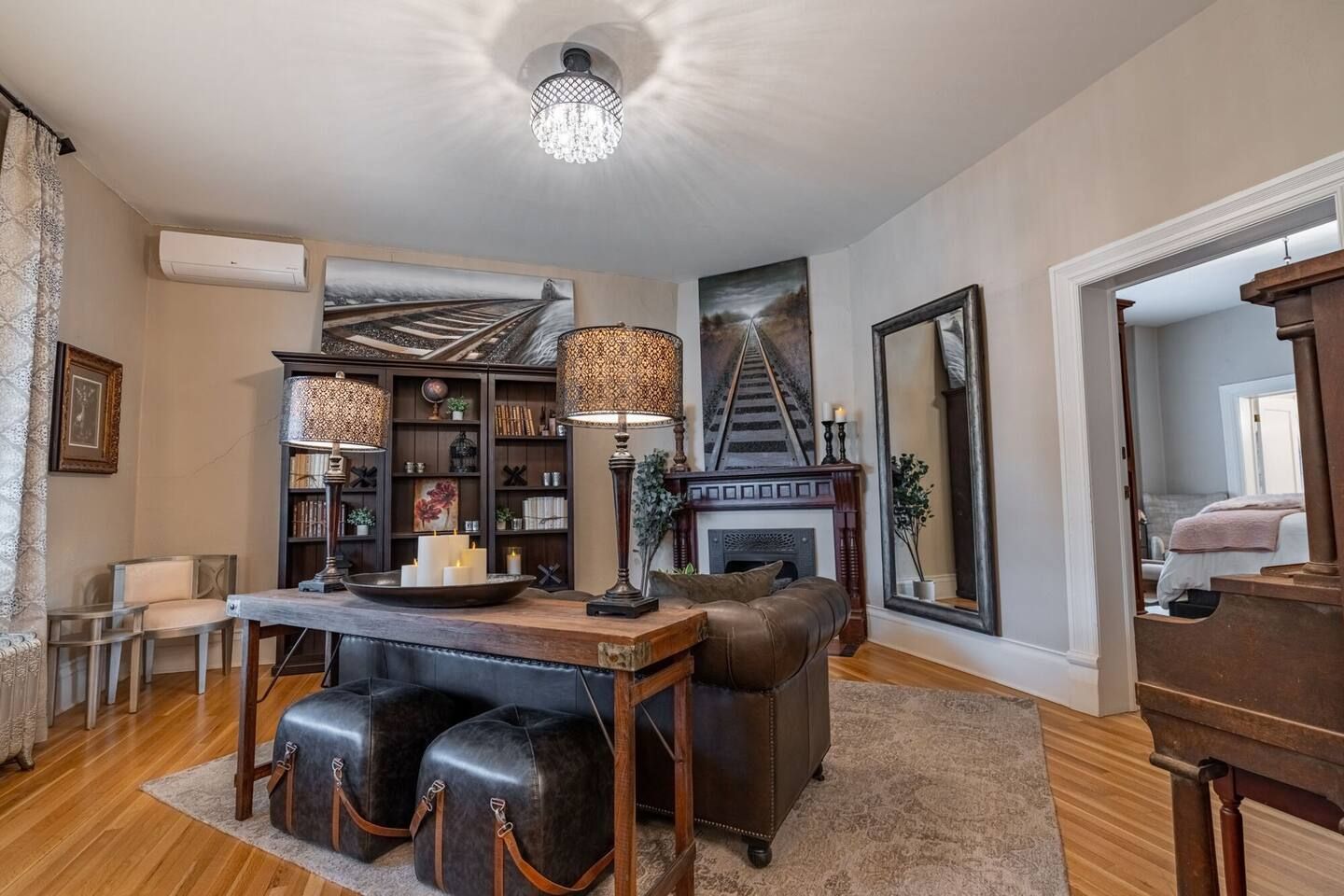 A living room with a fireplace, leather sofa, bookshelves, and a dining table.