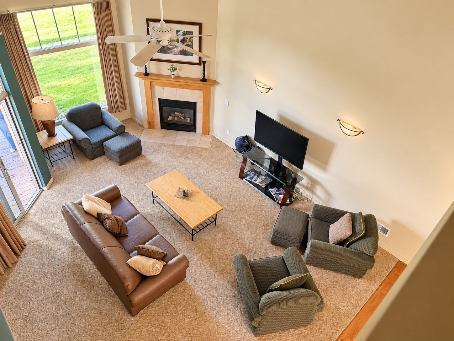 A spacious living room with a fireplace, a television, and a large window overlooking a grassy area.