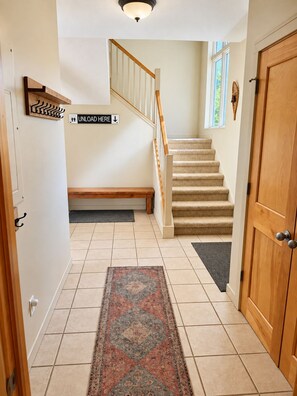 A hallway with a carpeted floor, a wooden bench, a staircase with a handrail, and a door with a round handle. - Purple Chair Landing. Ski-in/out condo (Bellaire)