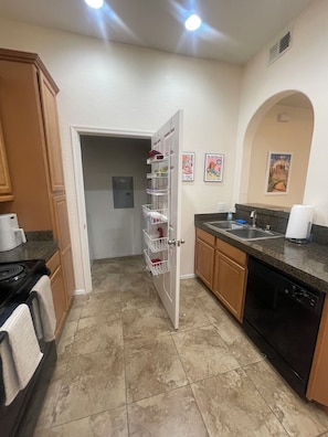 A kitchen with a stove, oven, and dishwasher, a door with a basket, and a wall with two framed pictures. - Fun in the Sun, Baseball, Luxury Condo! (Surprise)