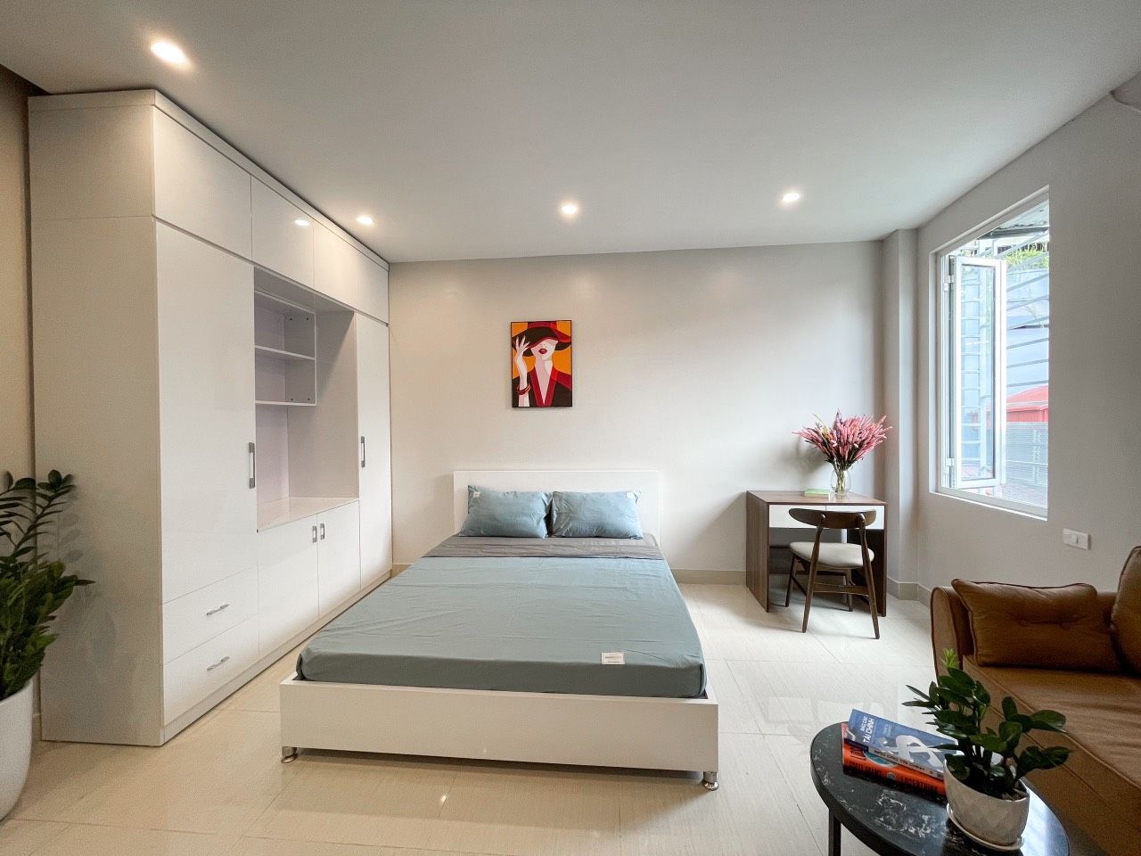 A modern bedroom with a bed, a desk, and a sofa.