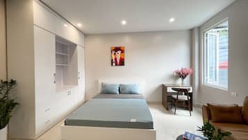 A modern bedroom with a bed, a desk, and a sofa.