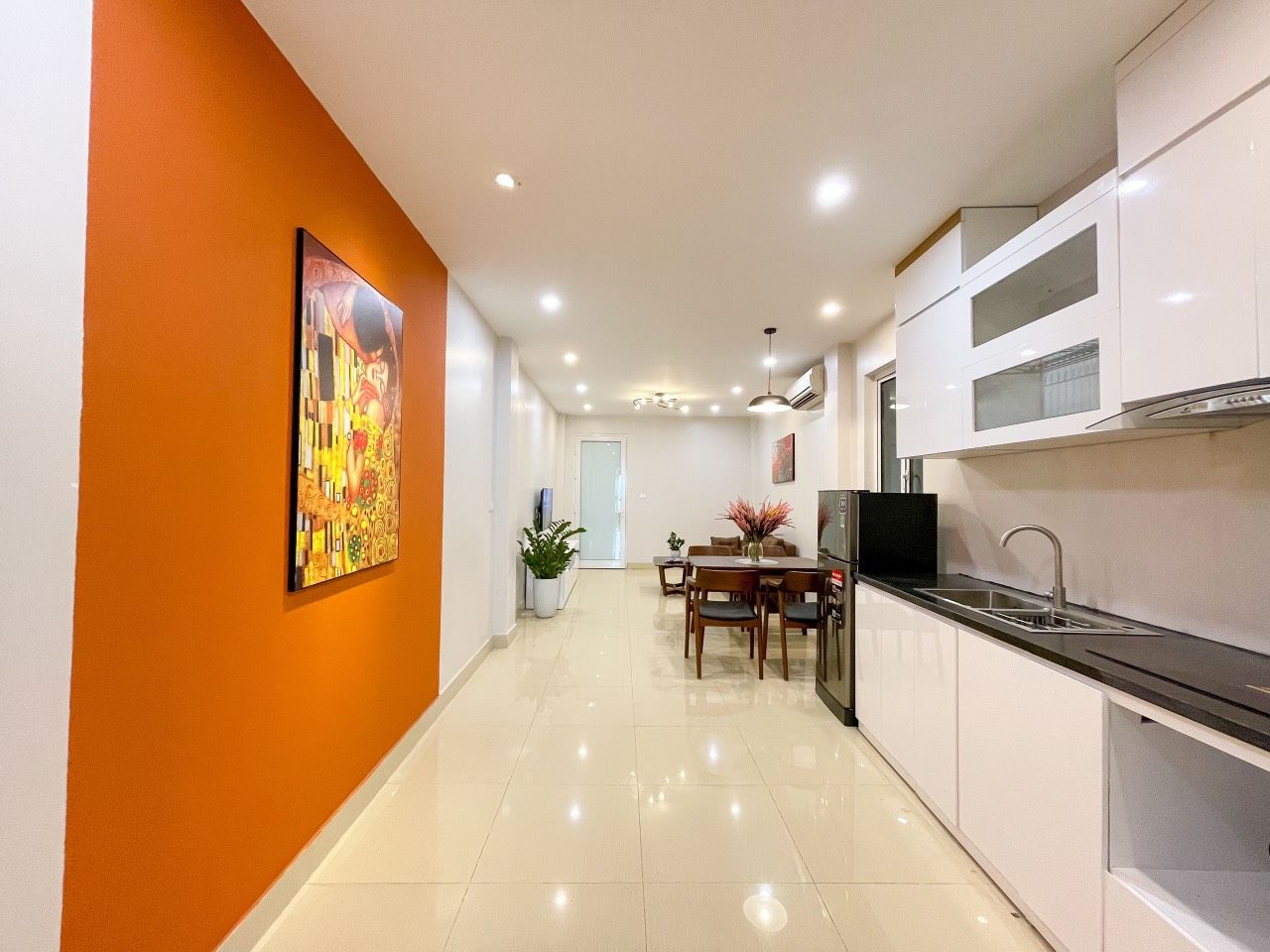 A modern kitchen with white cabinets, a black countertop, and a dining area with a table and chairs.