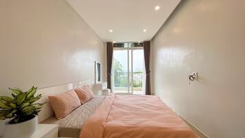 A bedroom with a bed, a nightstand, a potted plant, and a window with curtains.