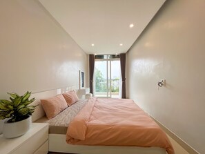 Une chambre à coucher avec un lit, une table de chevet, une plante en pot et une fenêtre avec des rideaux.