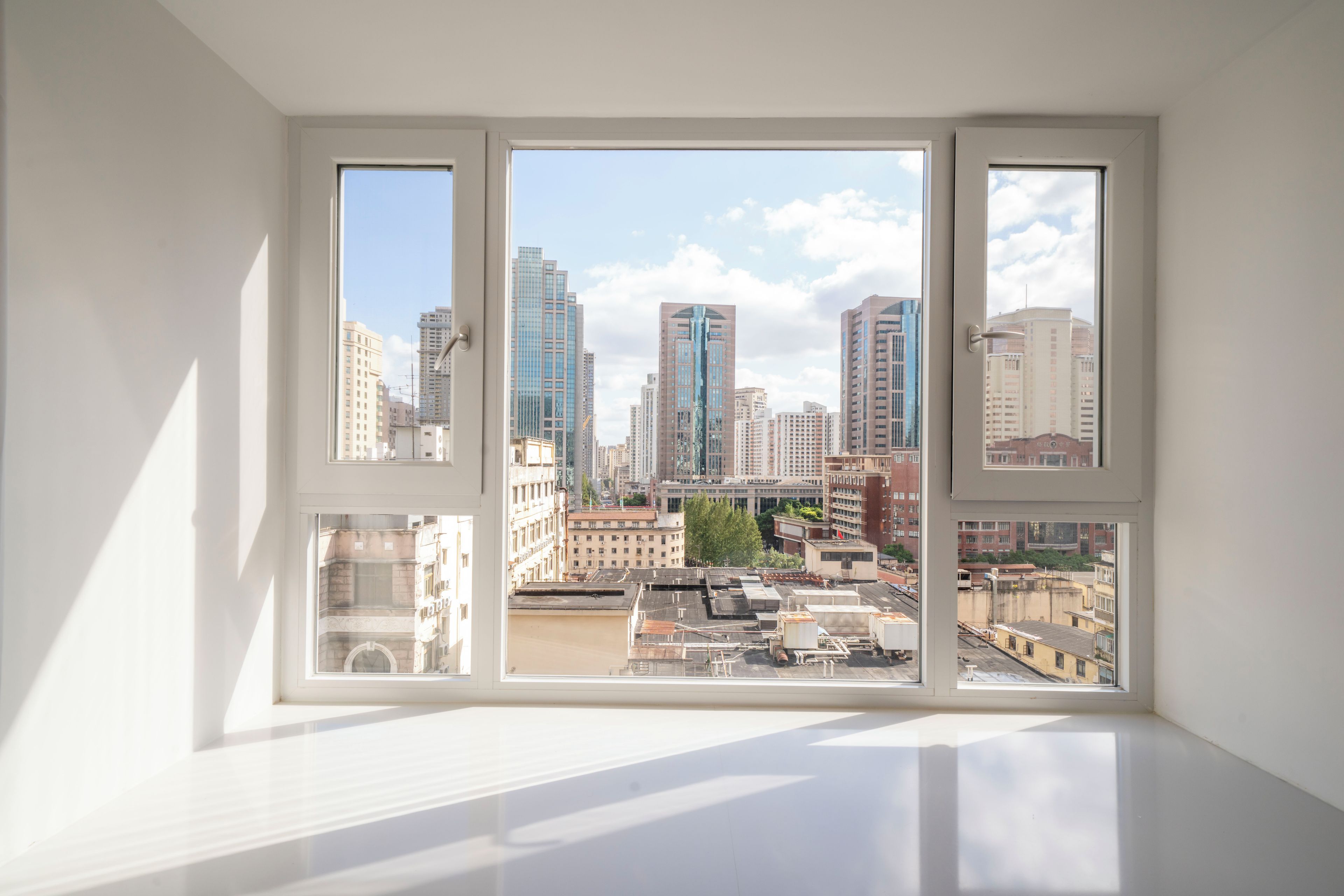 A room with a large window overlooking a cityscape with high-rise buildings.