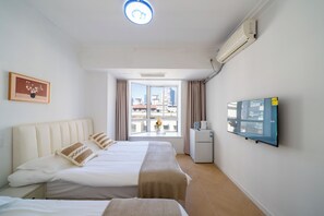 Quarto de hotel com cama, televisão, janela com cortinas e vista para a cidade.