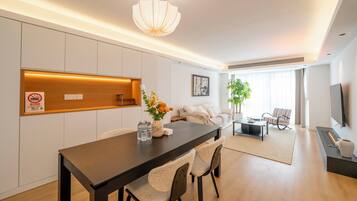 A modern living room with a dining area, a sofa, a TV, and a fireplace.