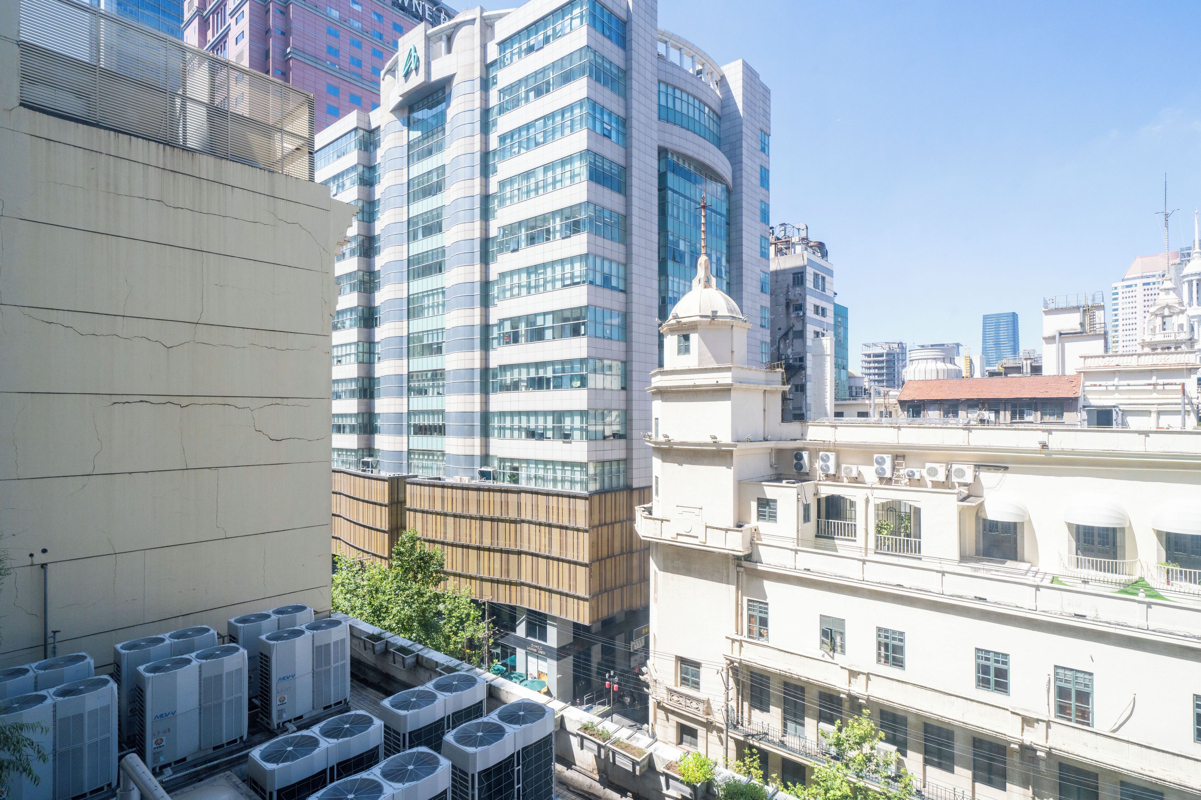 A high-rise building with multiple air conditioning units on the rooftop.