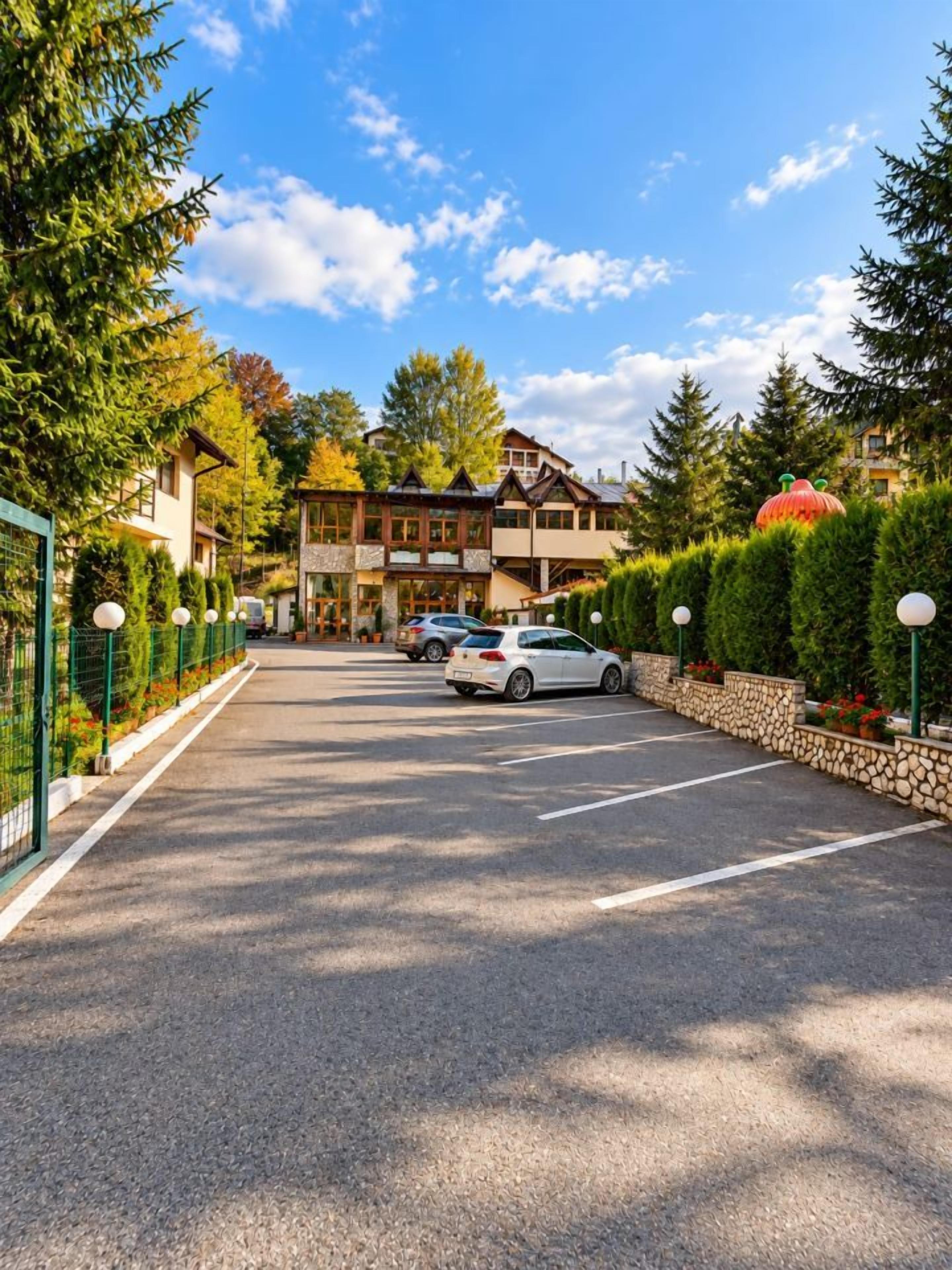 A parking lot with cars, a building with a sloped roof, and a clear sky.