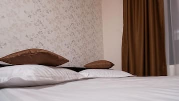 Ein ordentlich bezogenes Bett mit weißen Leinen und zwei braunen Kissen.