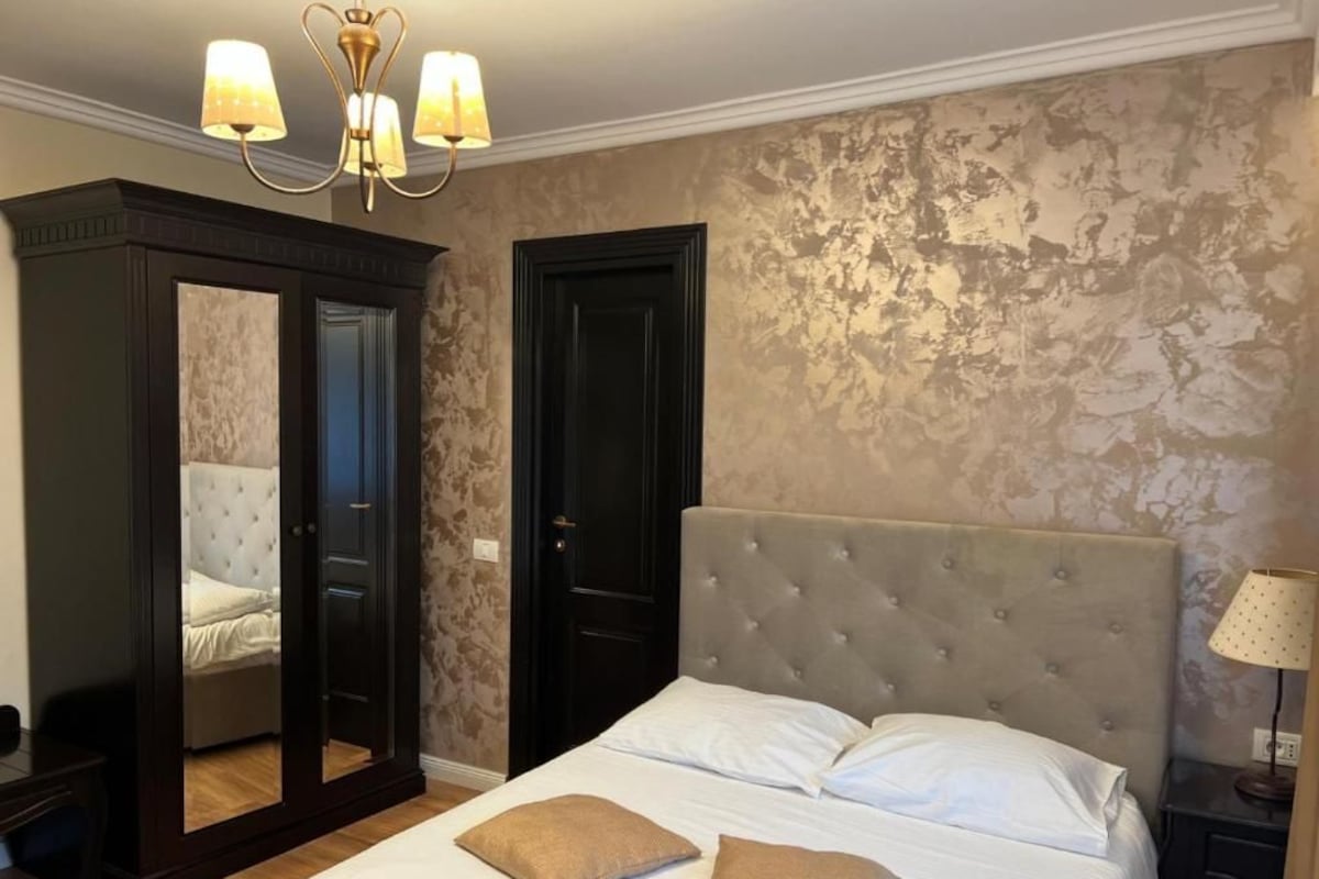 A bedroom with a bed, a wardrobe, and a mirror.