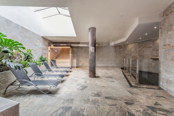 A modern indoor area with a skylight, a central pillar, and a row of lounge chairs. - Spacious 3-bedroom apartment with AC in charming El Raso (el raso)