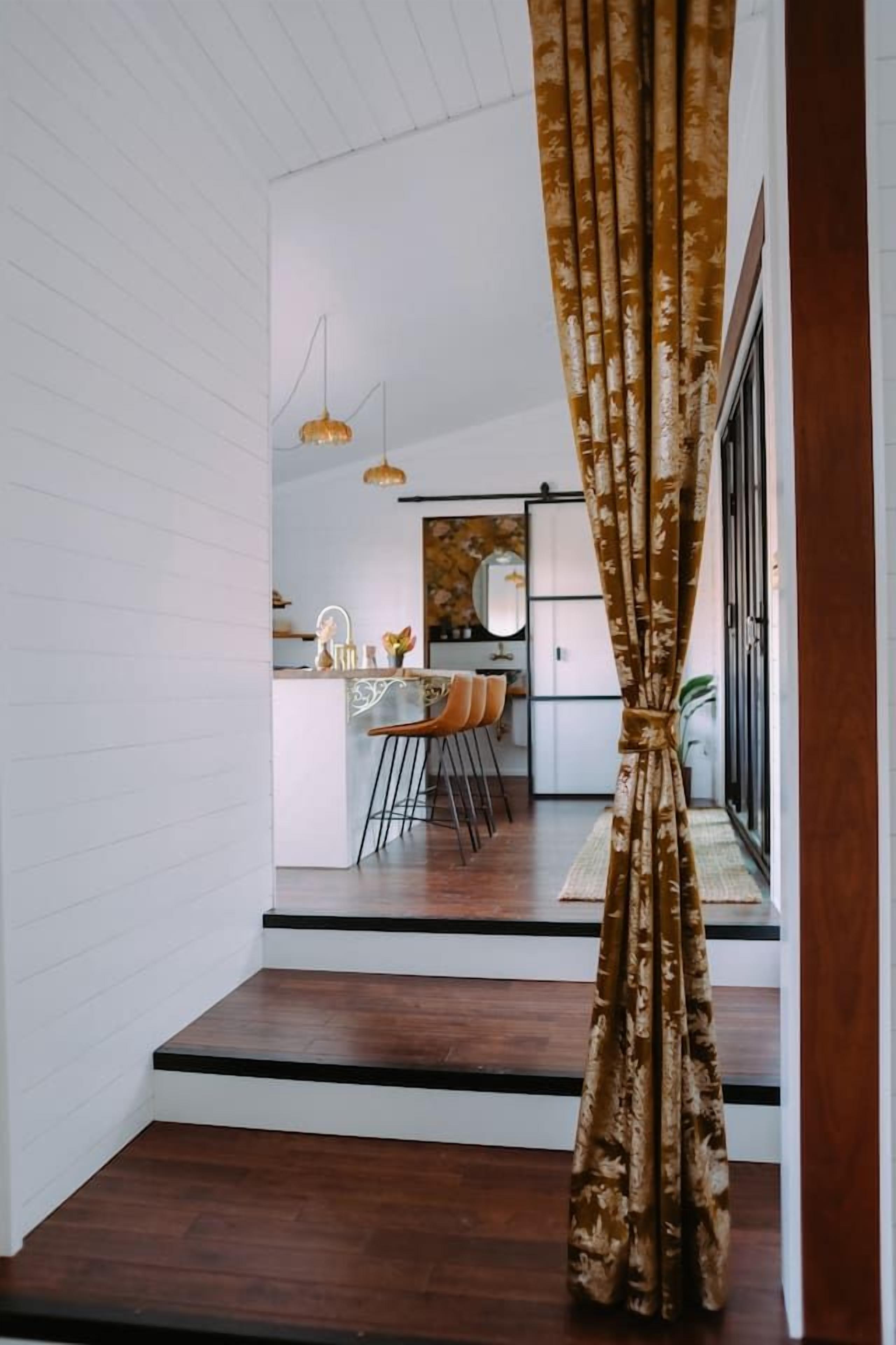 A staircase leading to a dining area with a kitchen in the background.