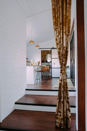 A staircase leading to a dining area with a kitchen in the background. - Dark City Solarium – Sauna + Hot Tub + Luxury (Black Mountain)