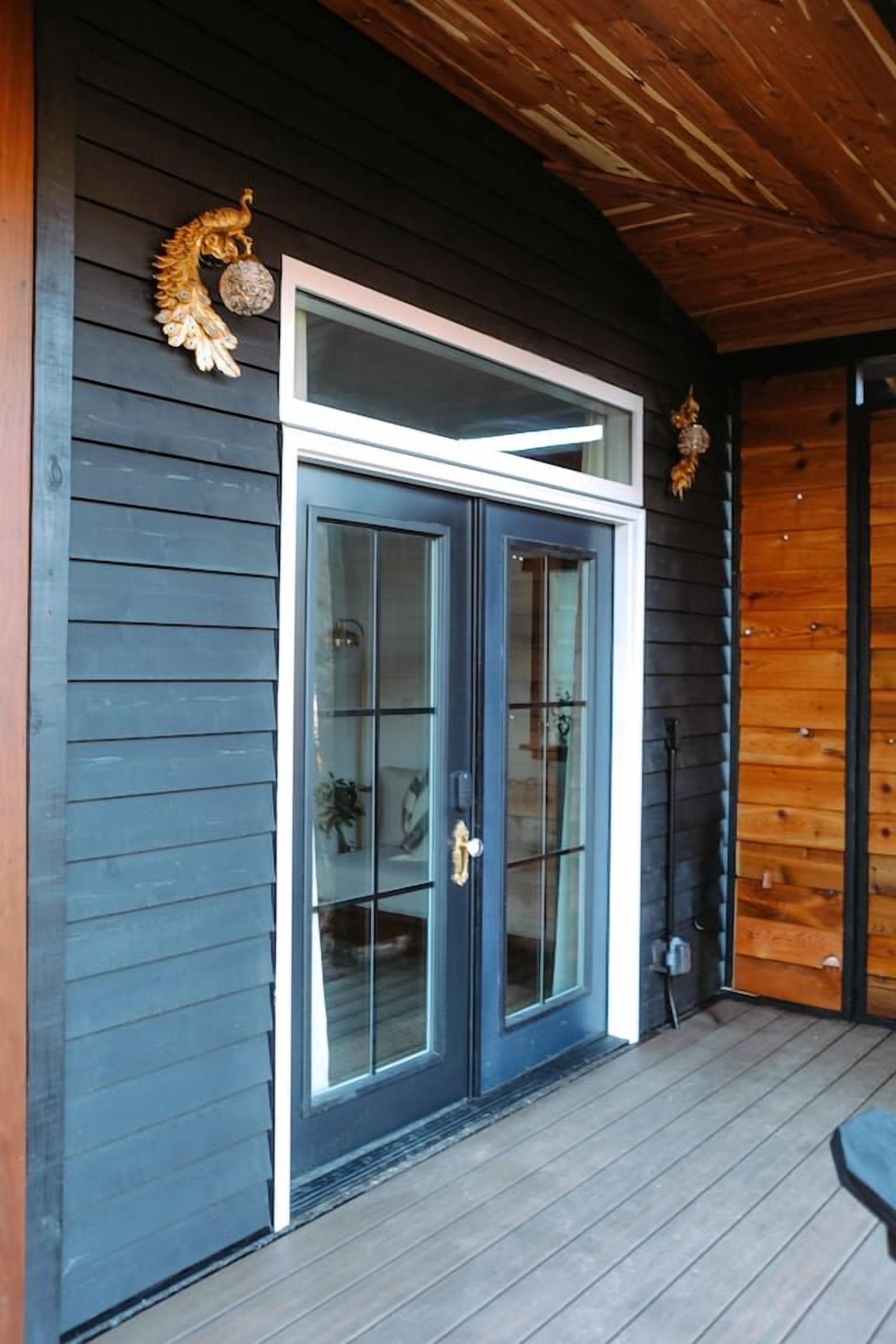 A wooden exterior with a dark blue door and glass panels, a wooden ceiling, and a small porch area.