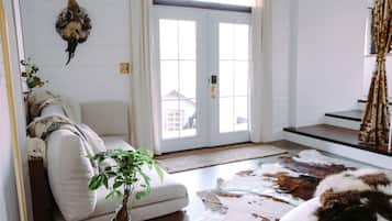 A living room with a sofa, a potted plant, a cowhide rug, and a mounted animal head.