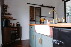 A kitchen with a wooden countertop, a sink, and a black refrigerator. - Dark City Solarium – Sauna + Hot Tub + Luxury (Black Mountain)