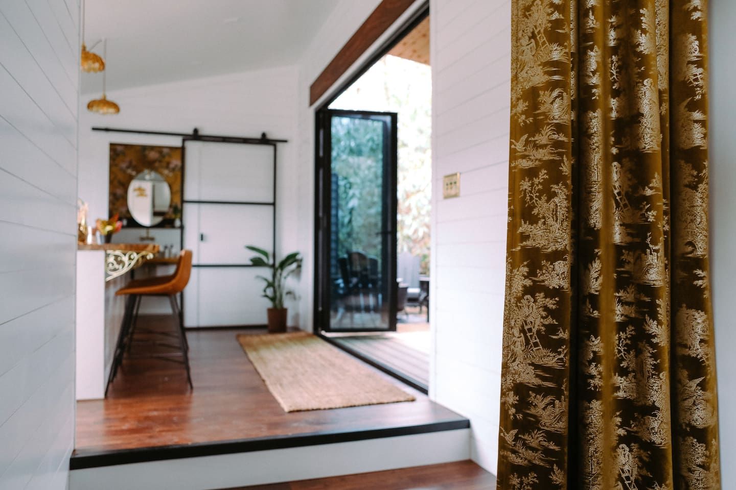 A modern interior with a wooden floor, a dining area with a chair and table, and a large window.