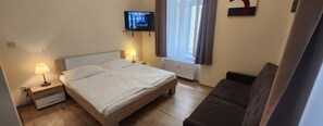A hotel room with a bed, bedside lamps, a television, a window with curtains, and a sofa. - Family friendly 2 Bedroom 2 Bathroom with Balcony Apartment. Pet friendly (Marianske Lazne)