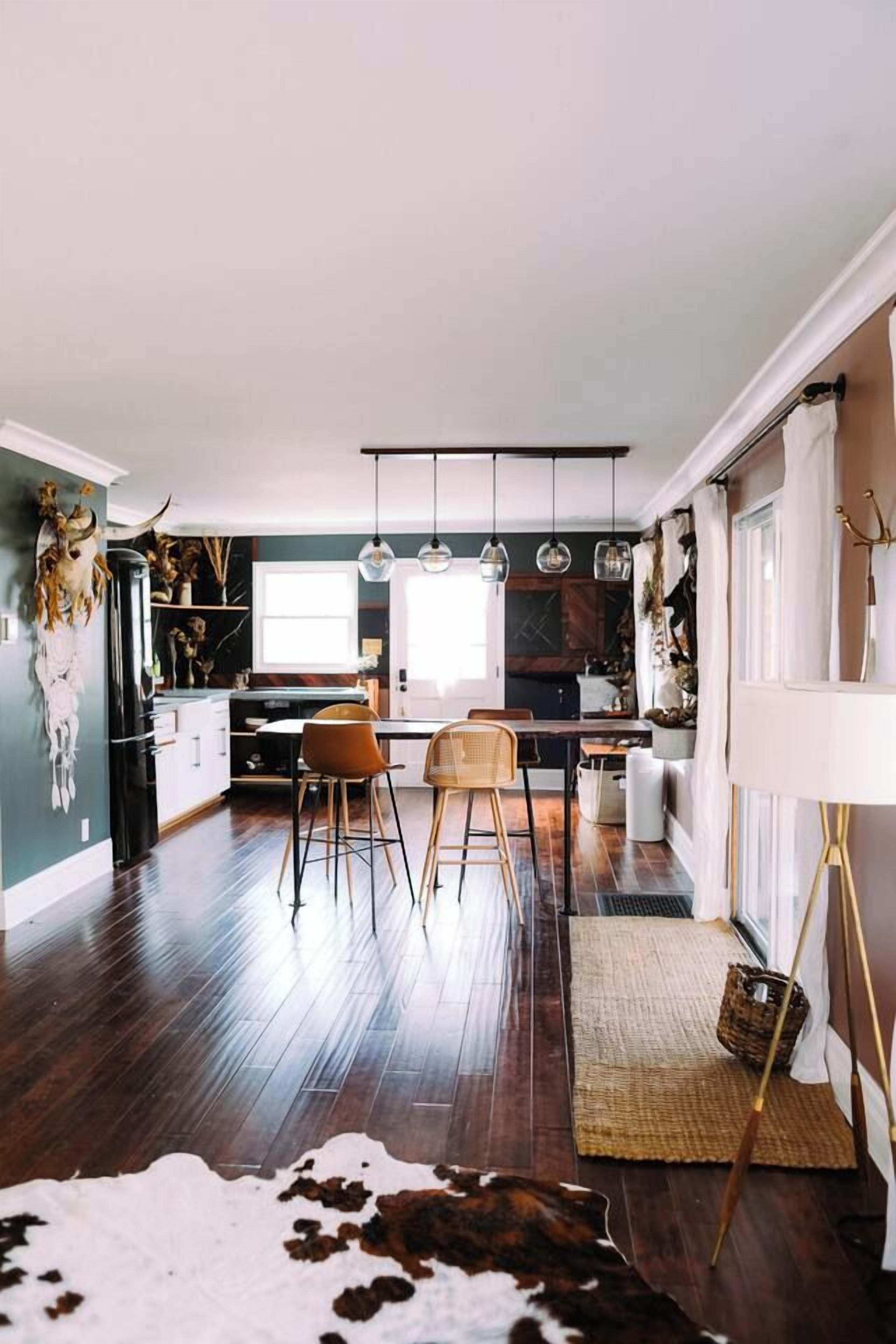 A modern kitchen with a dining area, wooden flooring, and pendant lighting.
