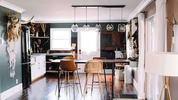 A modern kitchen with a dining area, wooden flooring, and pendant lighting.