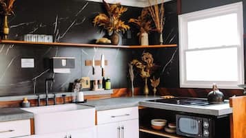 A modern kitchen with white cabinets, a black backsplash, and wooden flooring.