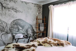 Una camera da letto con un grande affresco, un letto con una coperta in pelliccia, una scala in legno e una sedia.