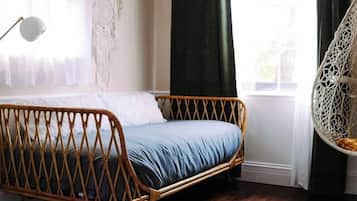 A room with a single bed, a hanging chair, a dreamcatcher, and a patterned rug.