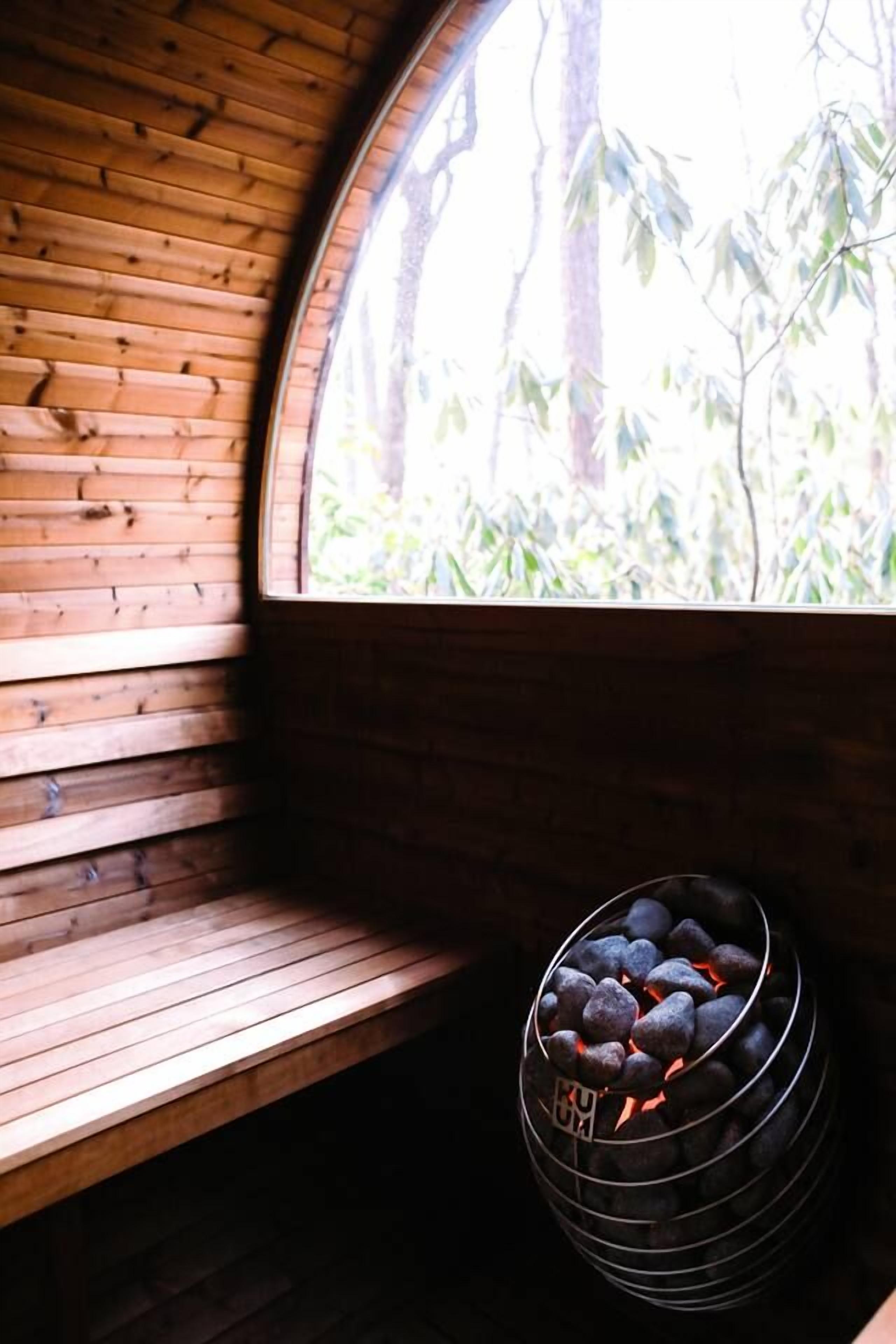 A wooden bench and a circular window with a view of trees.