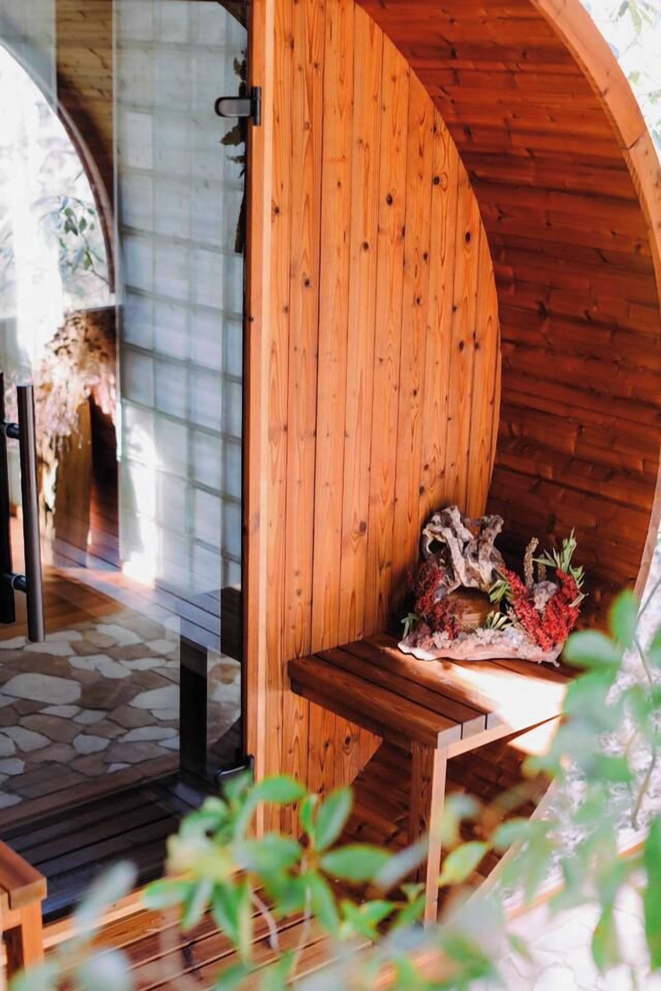 A wooden interior with a curved wall, a stone floor, and a table with decorative items.