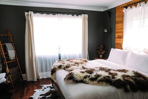 Un dormitorio con cama, una escalera, una ventana con cortinas y una pared de madera.