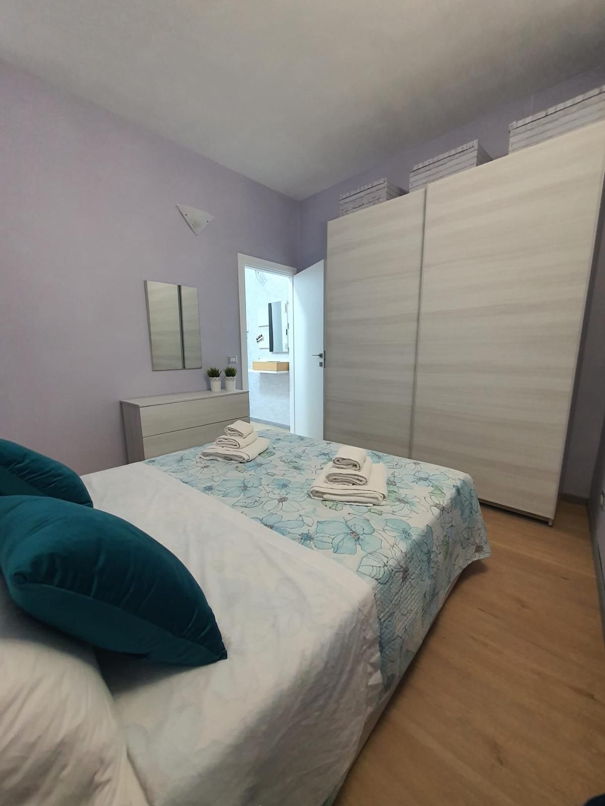 Una camera da letto con un letto, due cuscini, un comodino, uno specchio e un armadio.