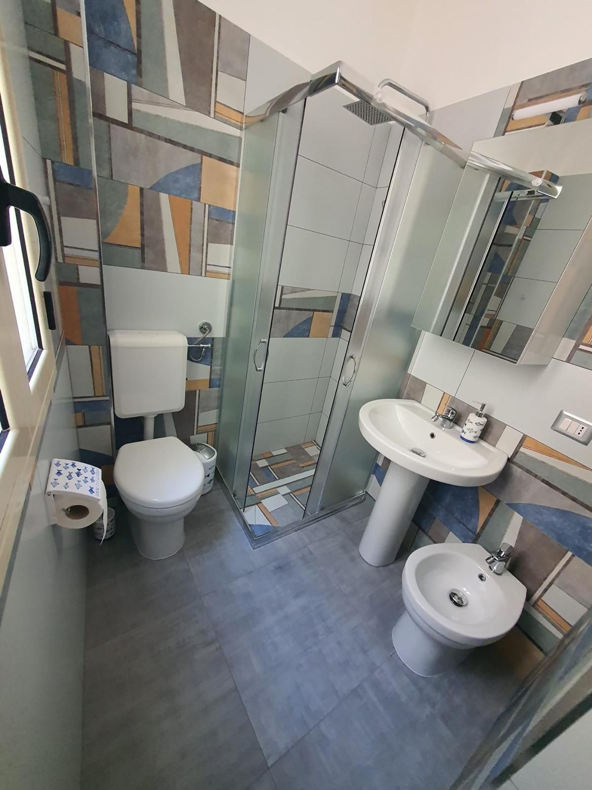 Un bagno con toilette, bidet e zona doccia vetrata.
