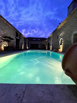 A swimming pool with stone walls and a clear blue sky.