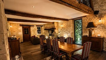 Un comedor amplio con una mesa y sillas de madera, una pared de piedra y un balcón con barandilla de hierro forjado.