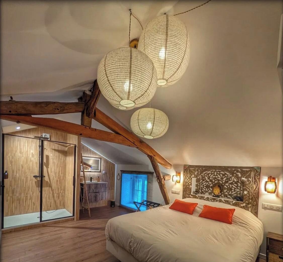 A bedroom with a large bed, wooden beams, and hanging paper lanterns.