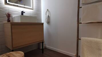 Un baño con tocador de madera, un espejo, un perchero y un taburete de madera.