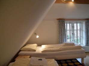 A bedroom with two beds, a window with curtains, and a radiator. - Holiday Apartment in Wrixum With Terrace (Wrixum)