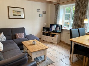 Un salon comprenant un canapé, une table basse, un téléviseur et un coin repas avec des chaises.