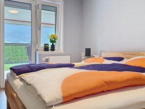 A bedroom with a bed, a window, and a view of greenery outside. - Apartment Reiter by Interhome (Kaprun)