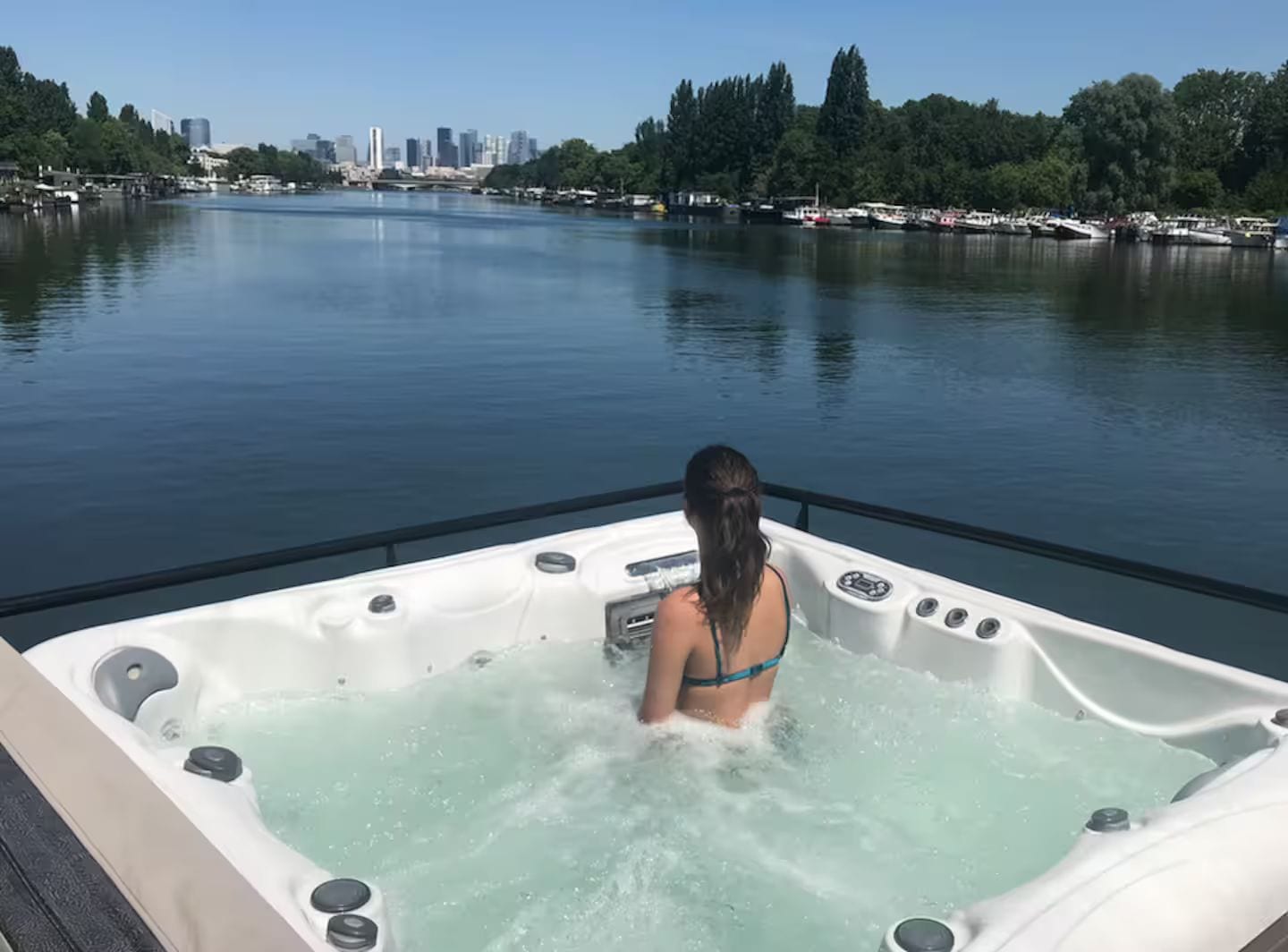 Une personne dans un jacuzzi, avec la silhouette d’une ville en arrière-plan.