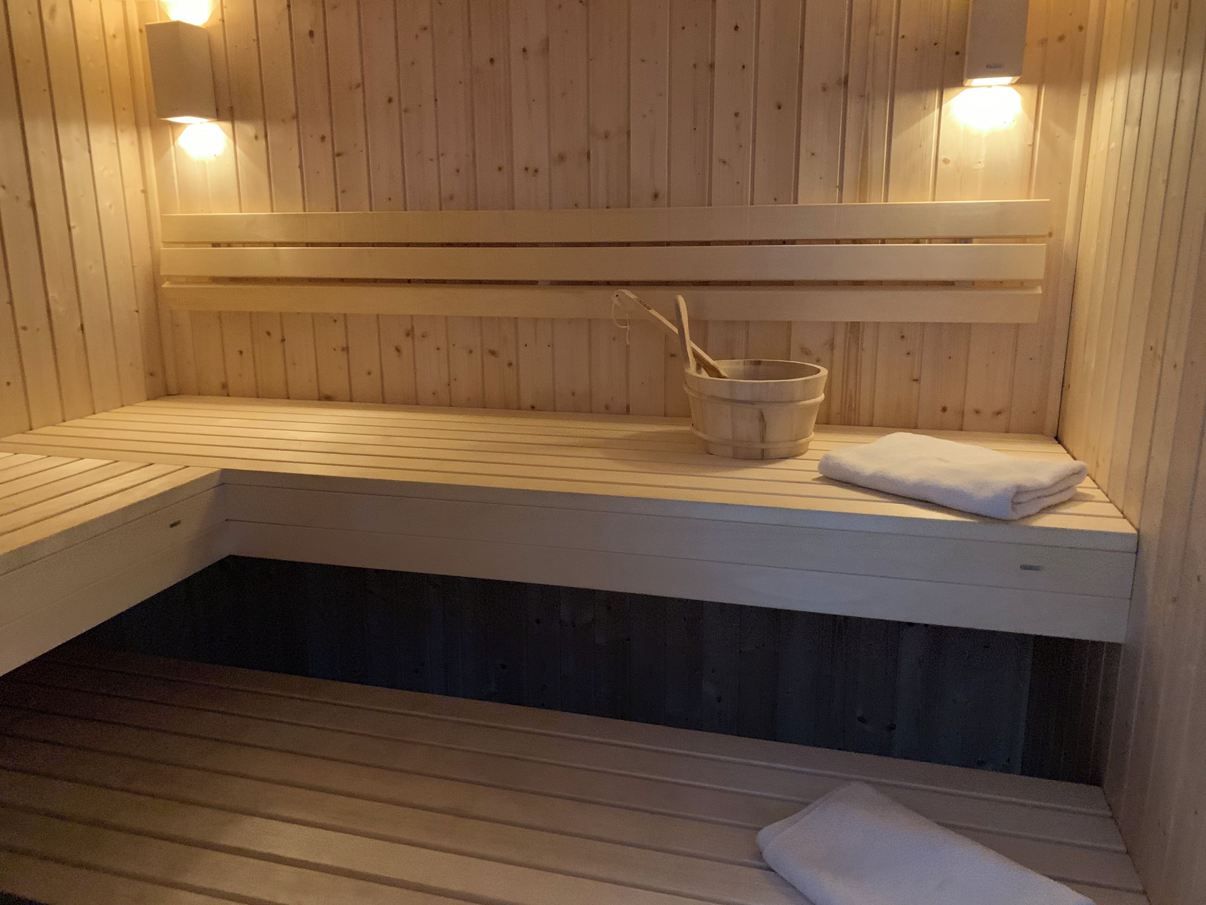 Un sauna avec des bancs en bois, un seau et une serviette.