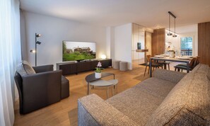A modern living room with a sofa, a coffee table, a TV, and a dining area with a table and chairs. - LUXURY APARTMENT NEAR SUNNEGGA EXPRESS WITH MATTERHORN VIEW (Zermatt)