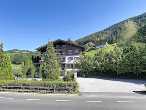 A multi-story hotel with balconies, surrounded by lush greenery and a mountainous backdrop. - Hochkönig am See by Interhome (Zell am See)