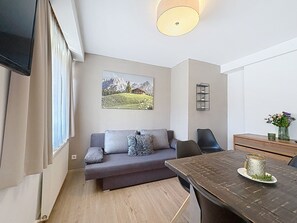 Ein modernes Wohnzimmer mit einer Couch, einem Esstisch und einem an der Wand befestigten Regal.