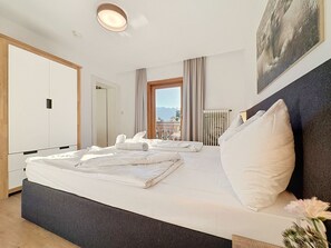 A hotel room with a large bed, a window with a mountain view, a radiator, and a wardrobe. - Schwalbenwand am See by Interhome (Zell am See)