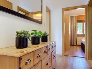 A hotel room with a wooden dresser, three potted plants, a mirror, and a view of another room through an open door. - Schwalbenwand am See by Interhome (Zell am See)