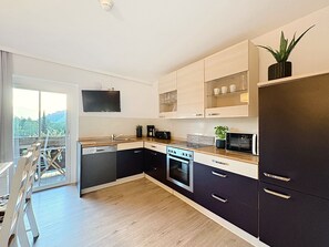 A modern kitchen with a dishwasher, stove, microwave, and cabinets. - Hundstein am See by Interhome (Zell am See)