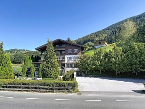 A multi-story hotel with balconies, surrounded by lush greenery and a mountainous backdrop. - Wiesbachhorn am See by Interhome (Zell am See)